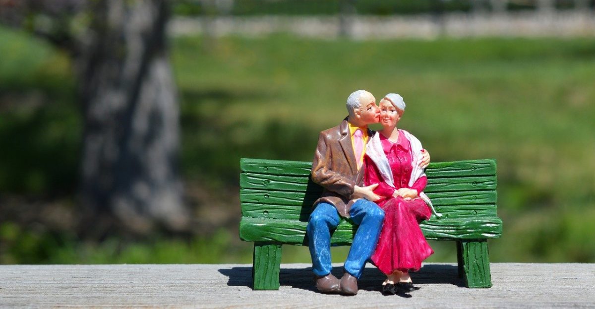 Casal de idosos apaixonados sentados no banco da praça
